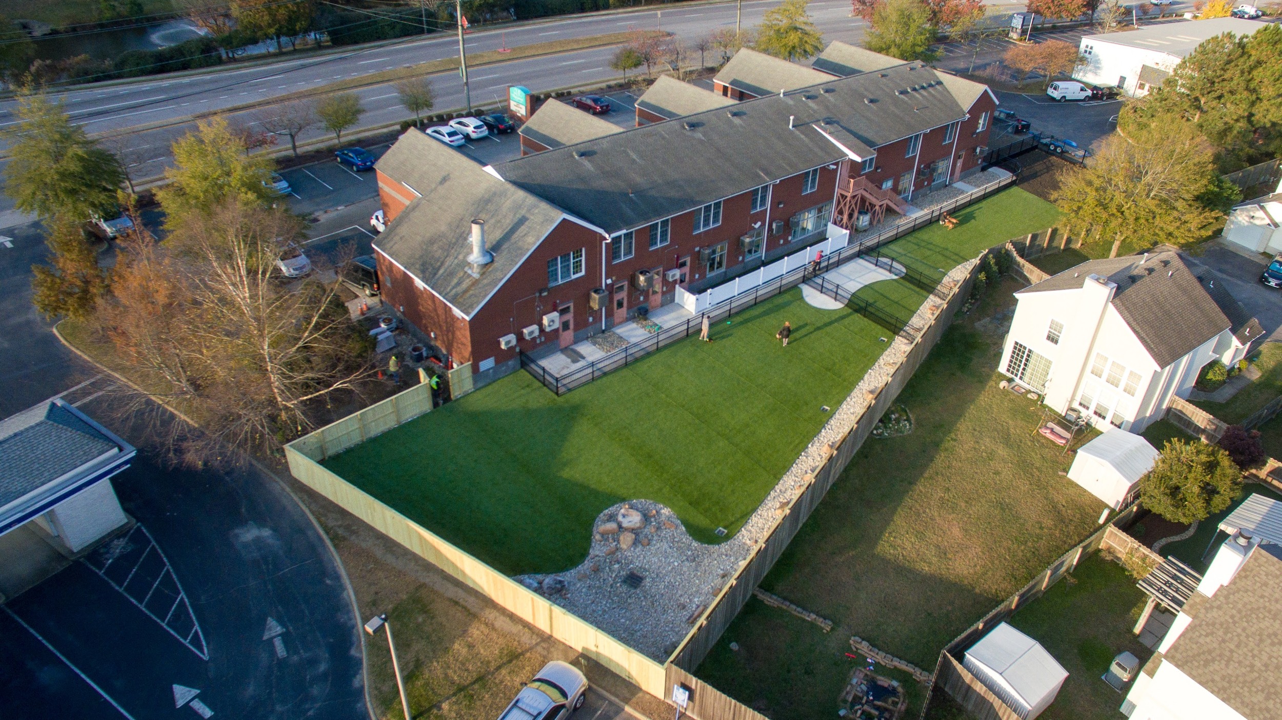 Aerial view of fenced dog exercise areas, turf, and curved concrete paths within an existing developed site