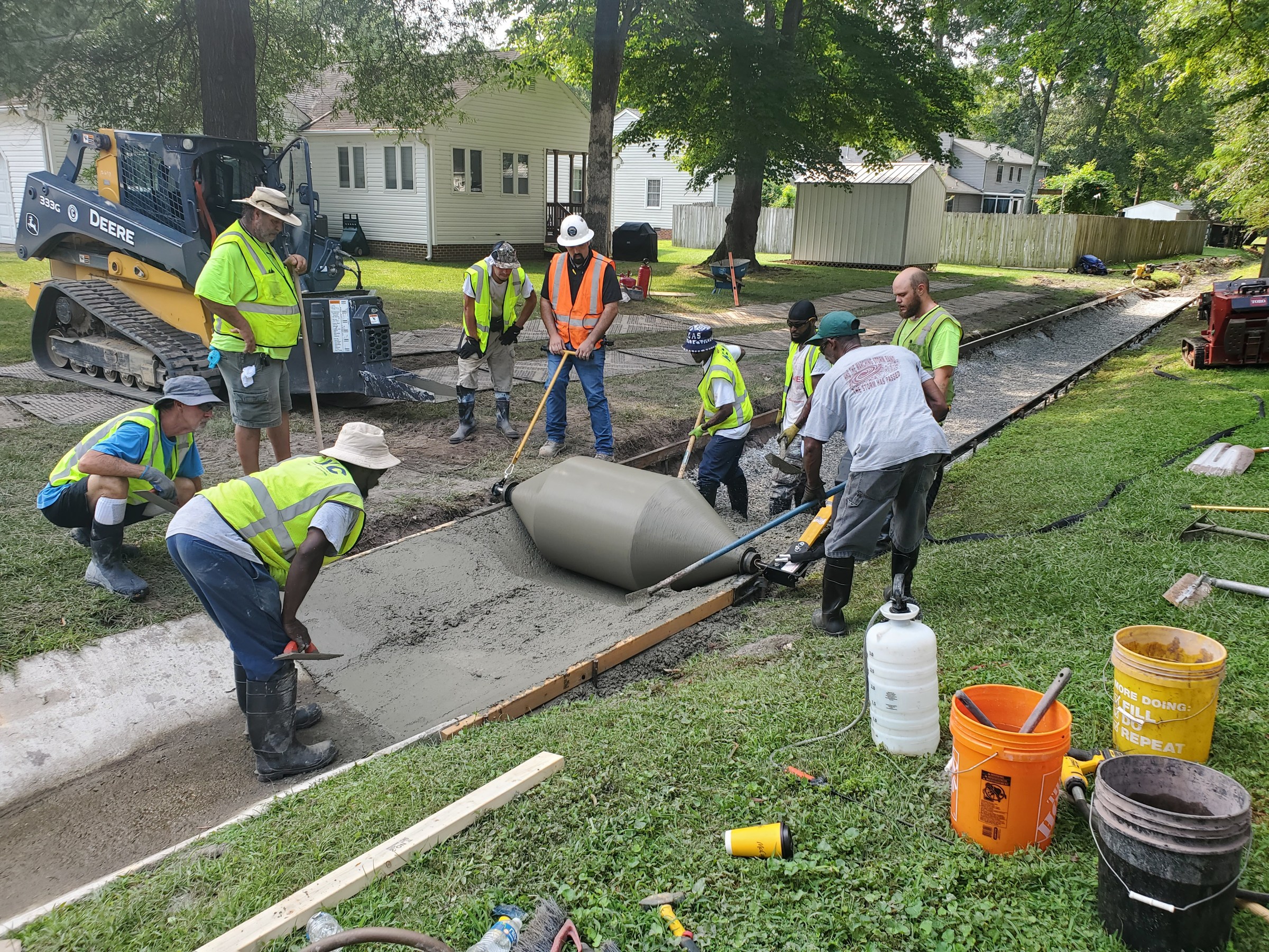 The crew works the fresh concrete to the formed channel profile.