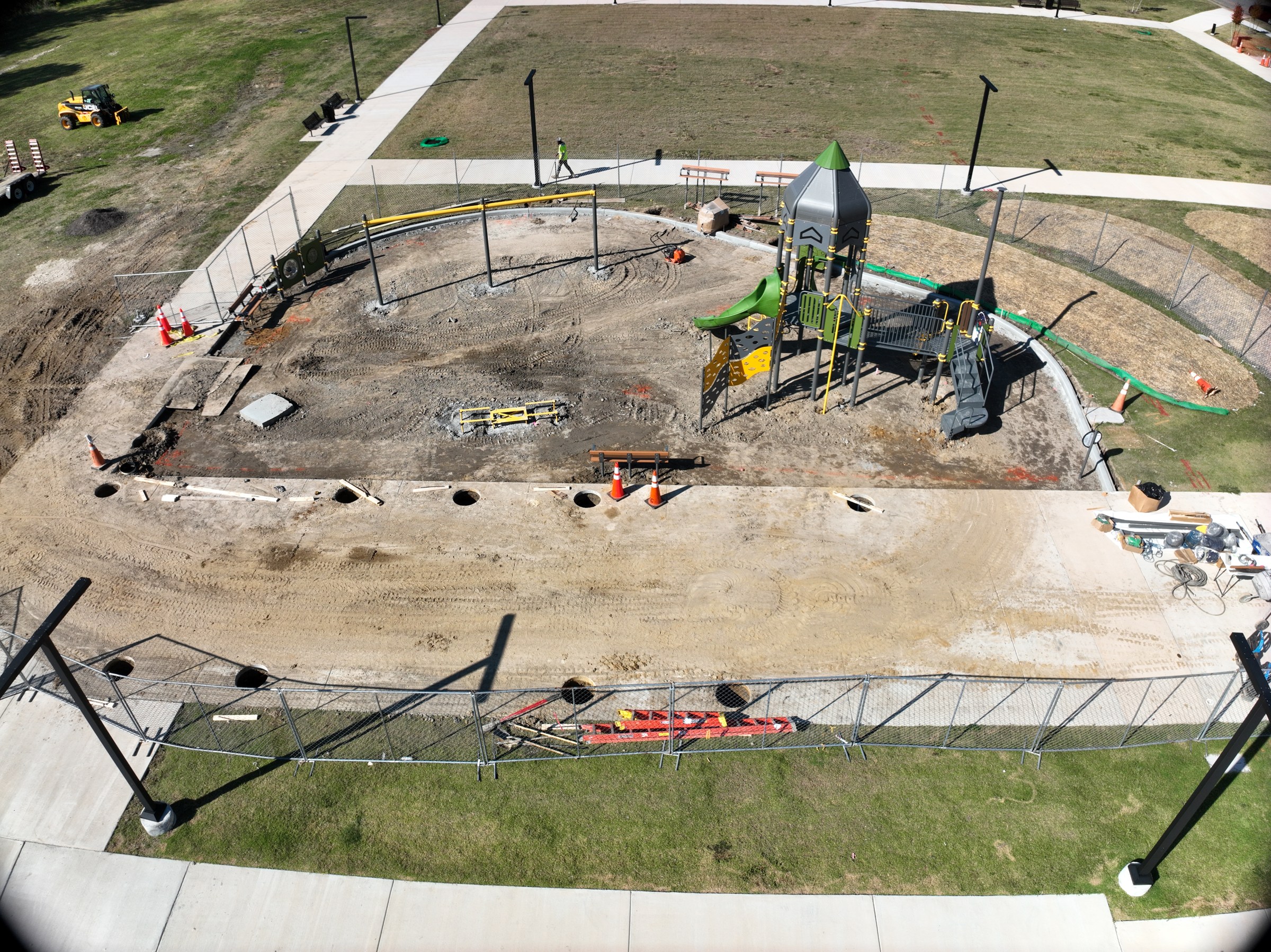 Play structures take shape as foundations and surrounding sitework progress.